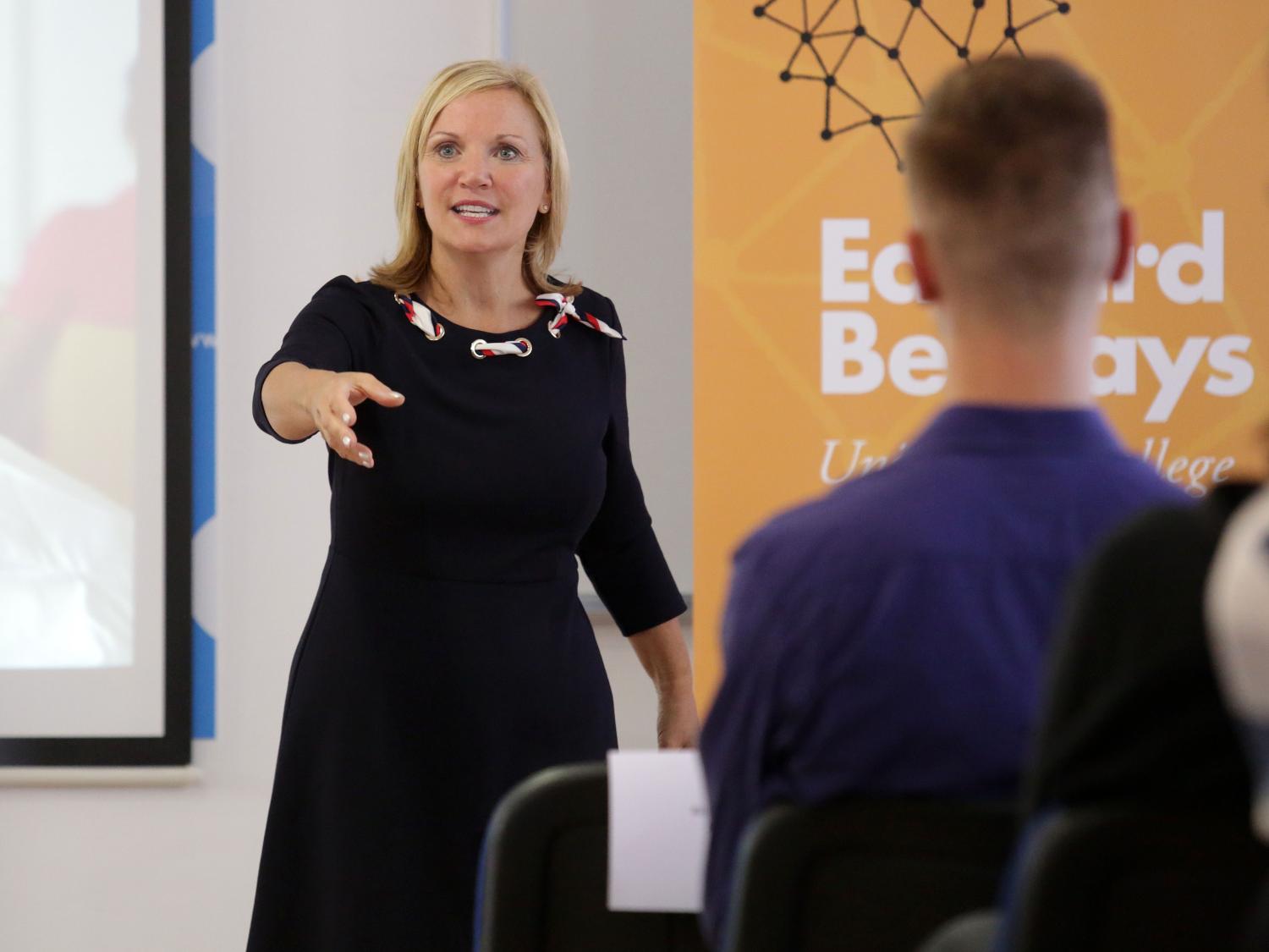 woman gesturing while speaking to a class of students