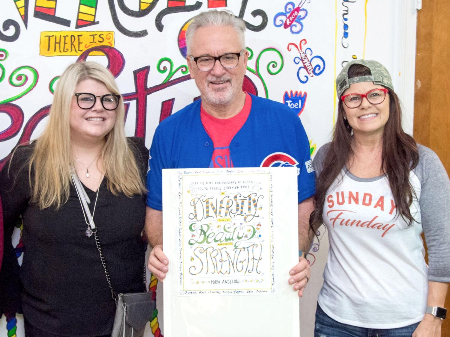 three people pose in front of a mural