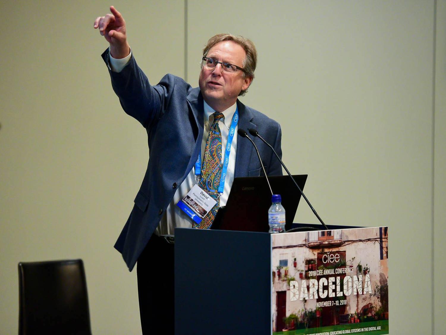 Professor Livert gesturing with his arm up during a lecture
