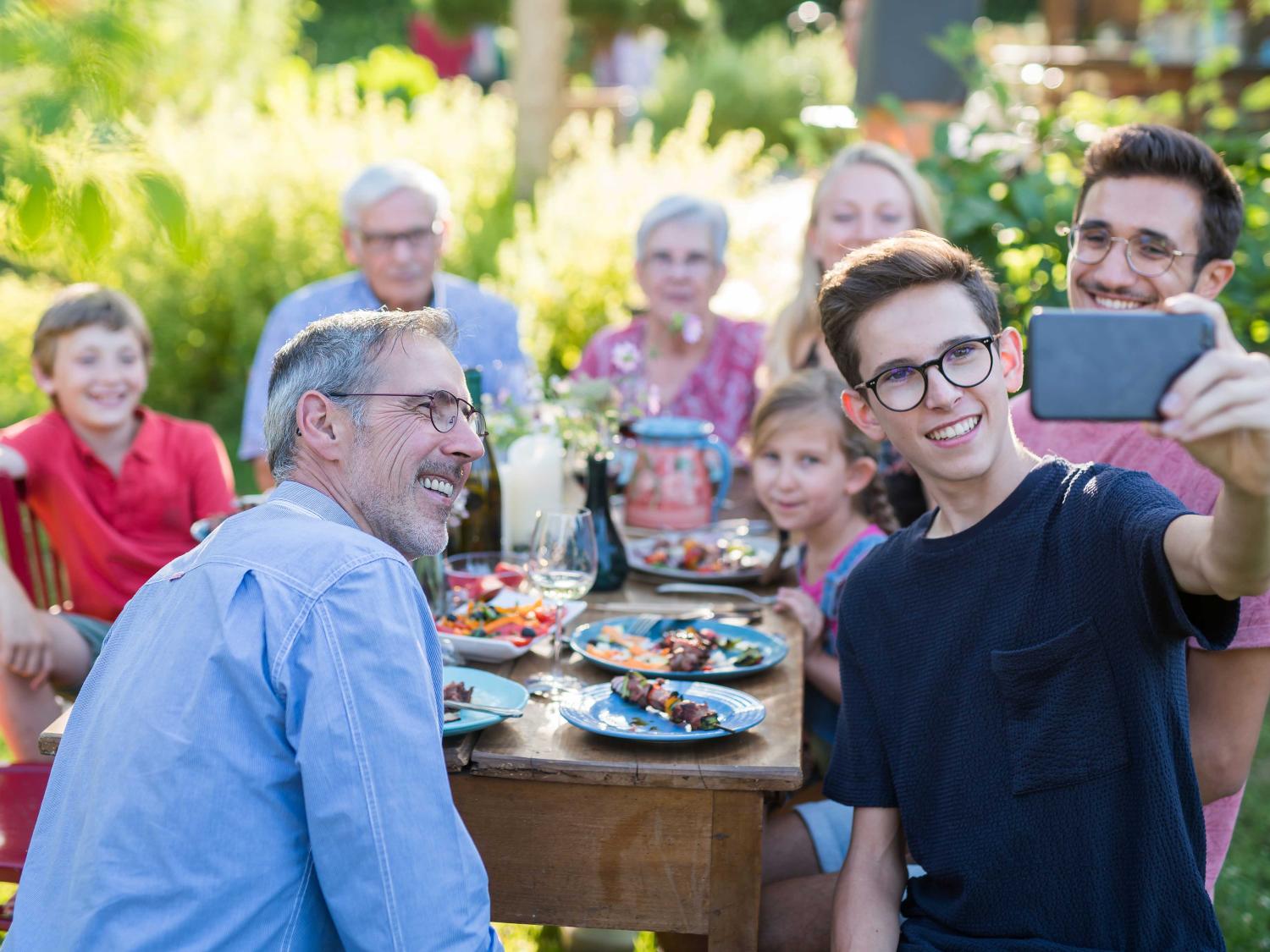 teen taking selfie at family dinner outdoors