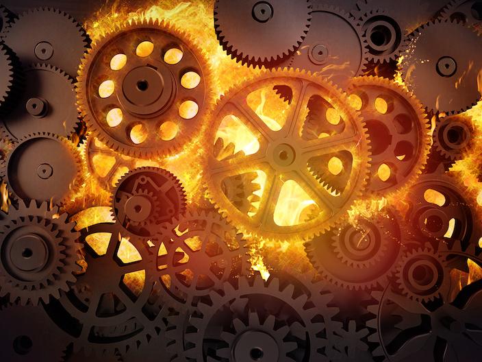 A stock image of gears surrounded by flames.
