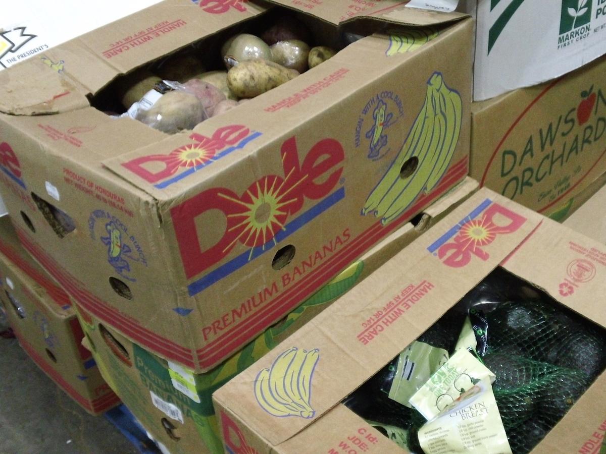 Boxes of food sit on the floor of the food bank warehouse.