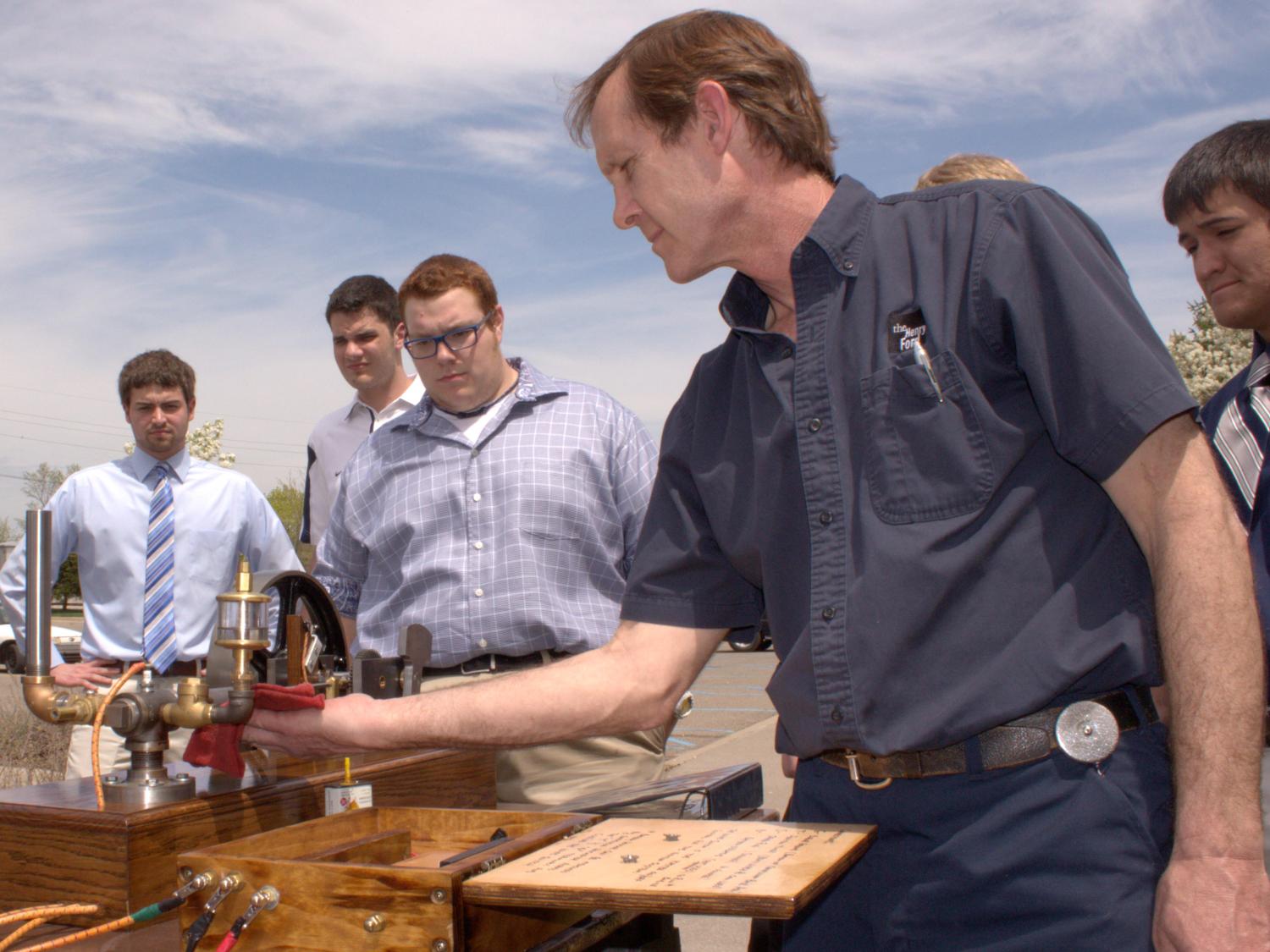 Penn State Beaver students teach a member of the Henry Ford Museum staff how to operate the Kitchen Sink Engine.