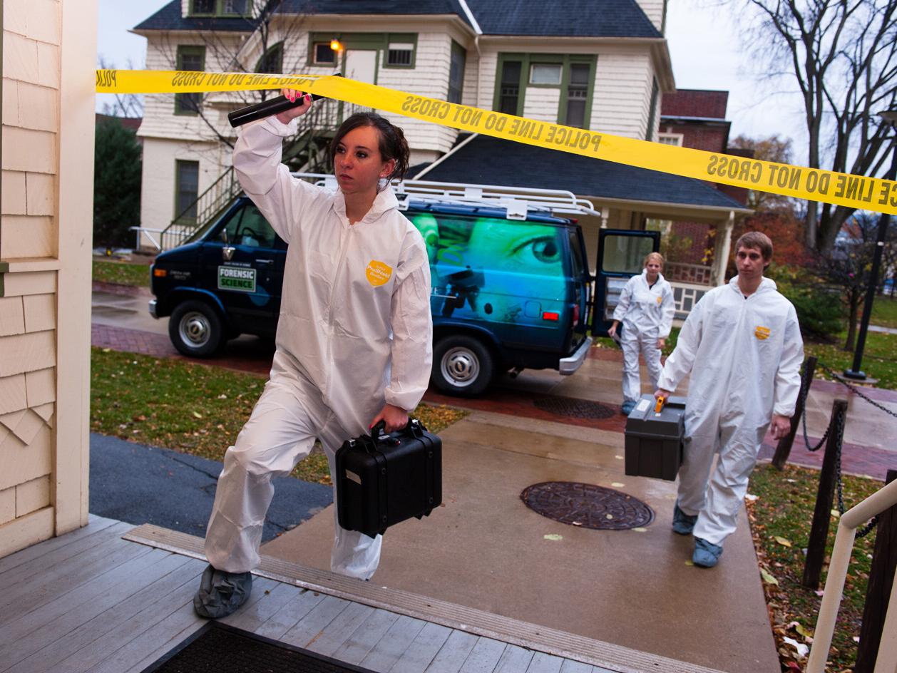 female student crossing police line at mock crime scene
