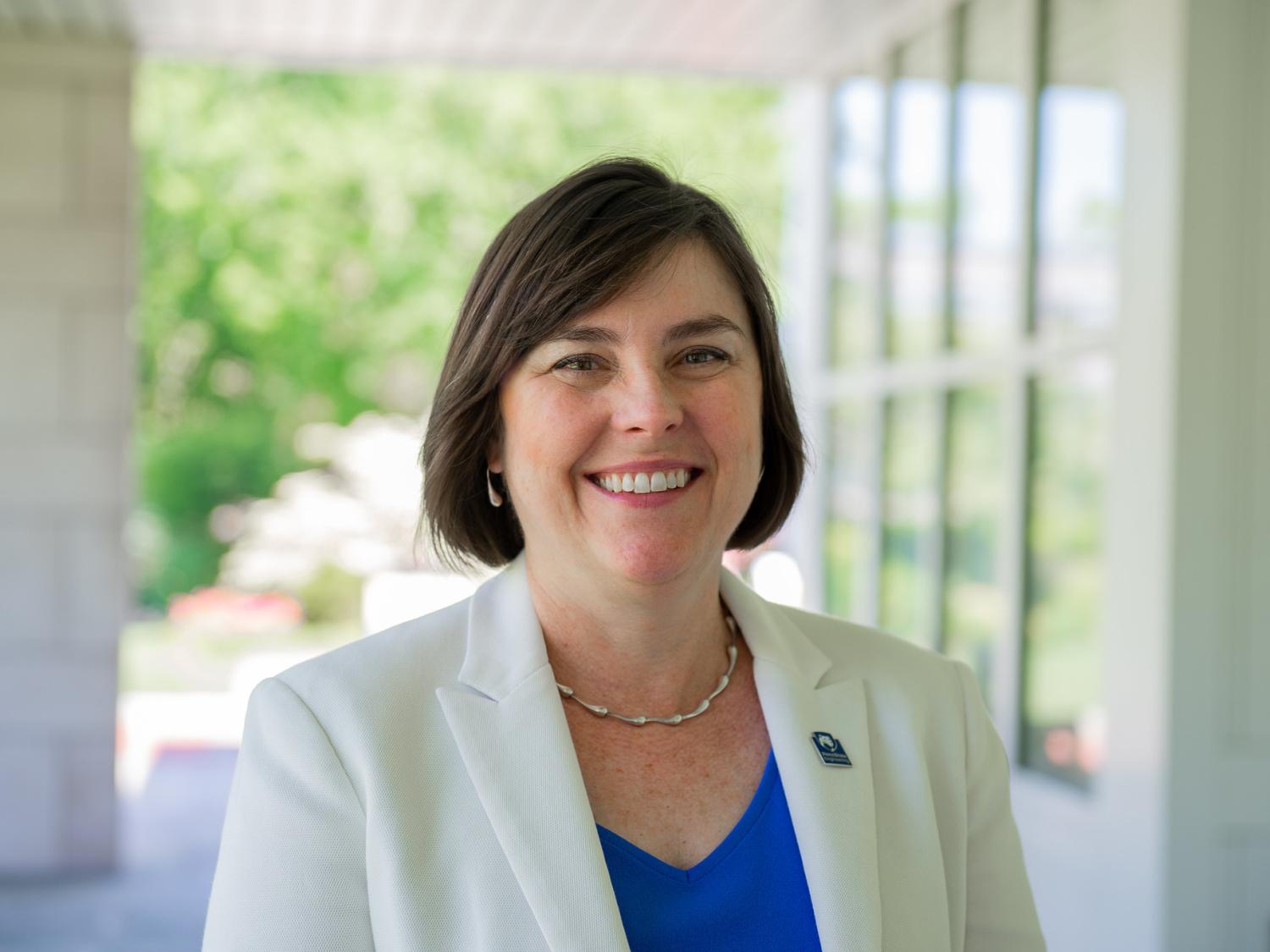 A professor stands in the Hintz Alumni Center smiling.