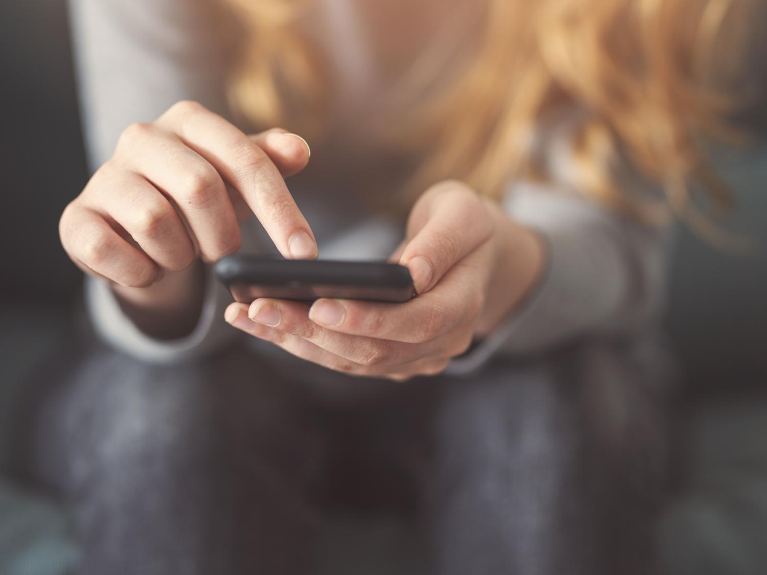 A teenage girl scrolls through a smartphone