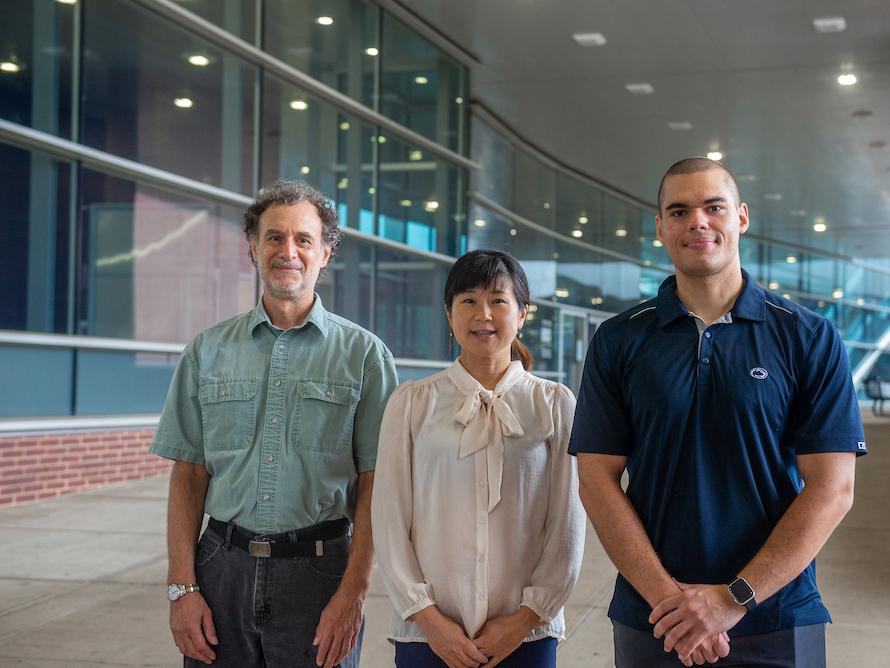 Two men and a woman pose outside for a group photo. 