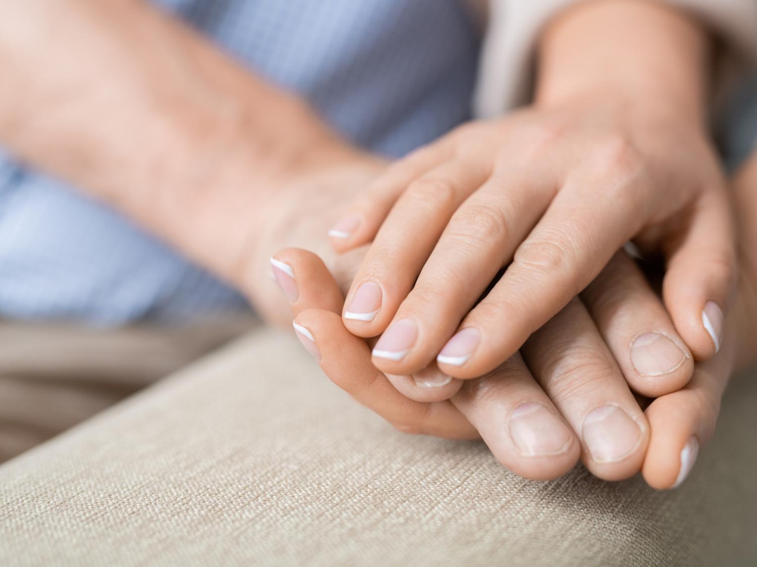 Close up of two hands holding another in support