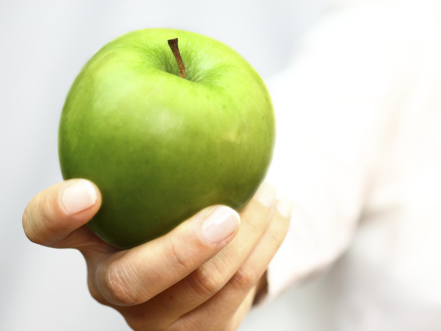 Hand holding a green apple
