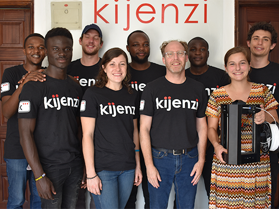 Nine people stand face forward while smiling. 
