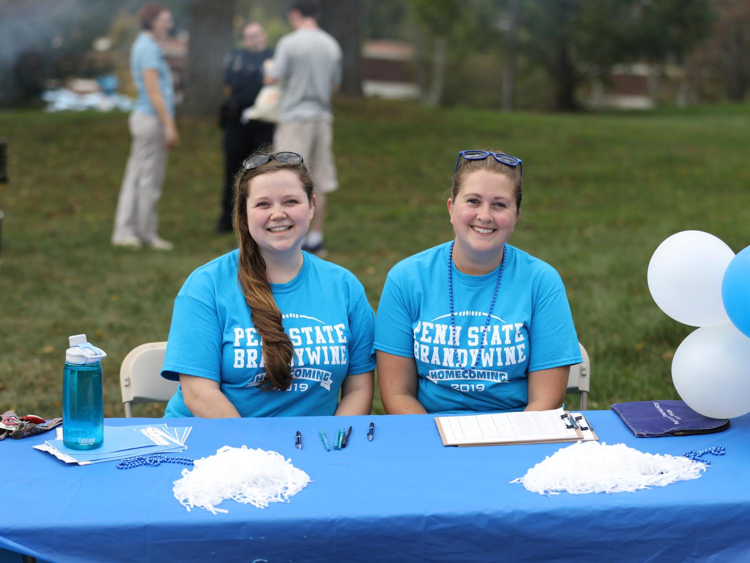 Two Penn State Brandywine volunteers sit at the registration table at the 2019 homecoming celebration.