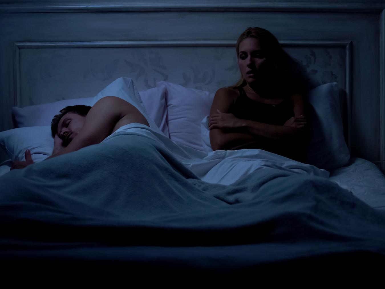 Man sleeping, woman awake in bed