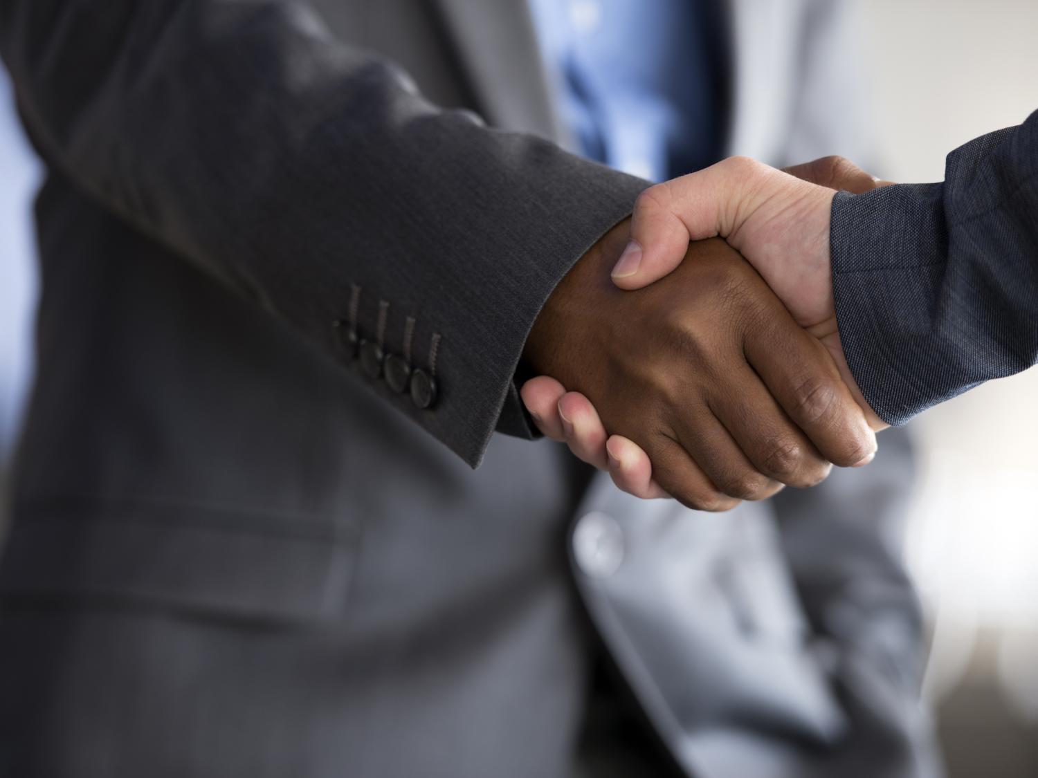 African American and white man shaking hands.