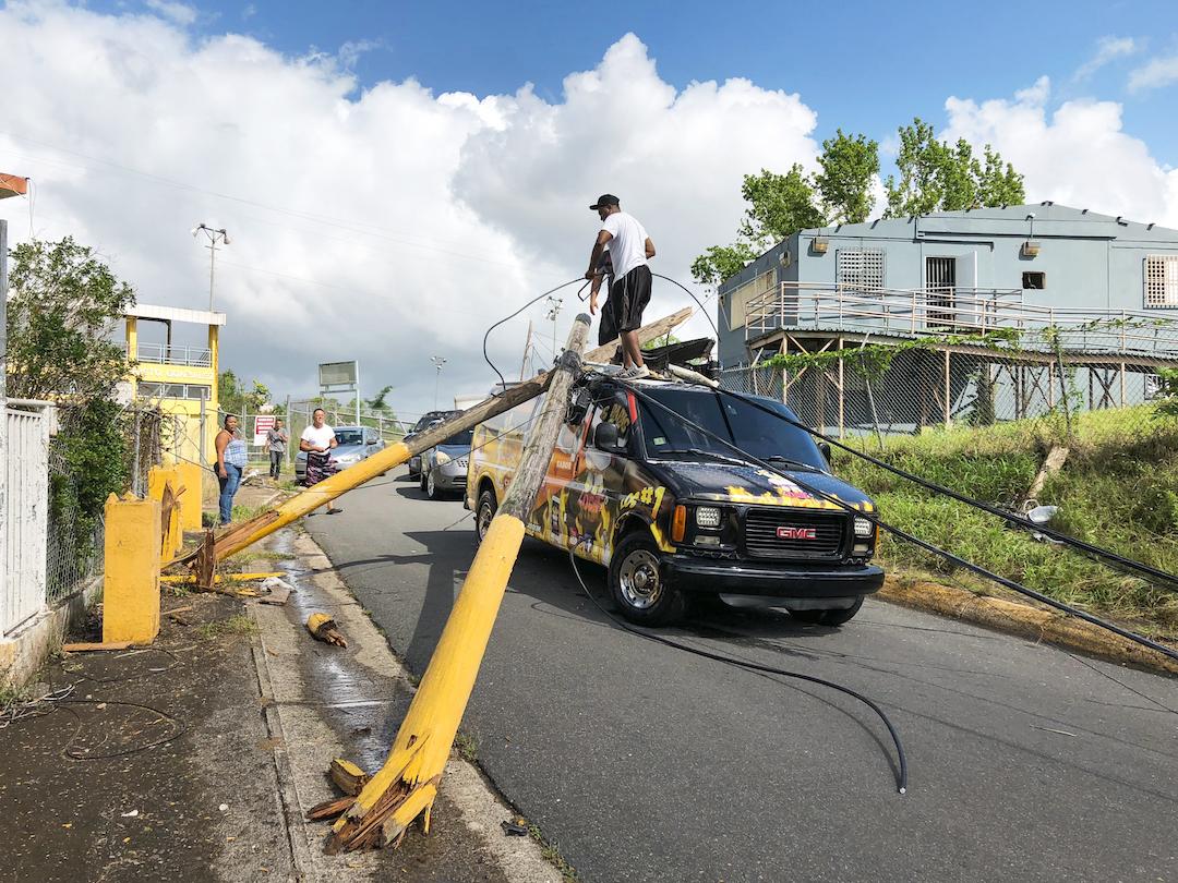 People attempt to remove broken power poles that landed on top a food truck in Vega Alta, Puerto Rico after Hurricane Maria.