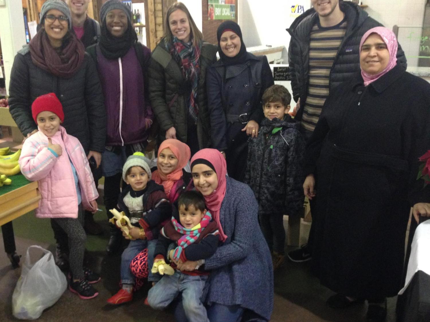 Medical students pose with a refugee family at a farmer's market.