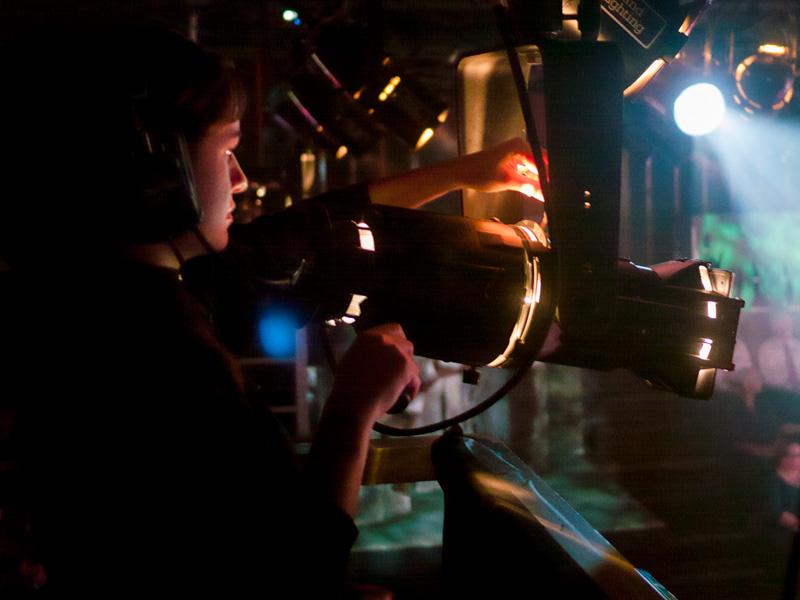 A crew member shines a spotlight on stage at the Pavilion Theatre