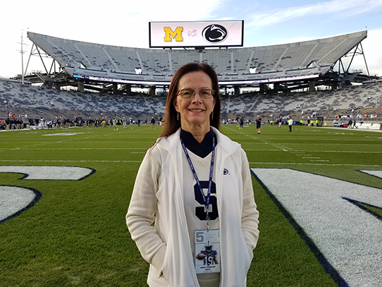 Woman wearing white stands on a football field. 