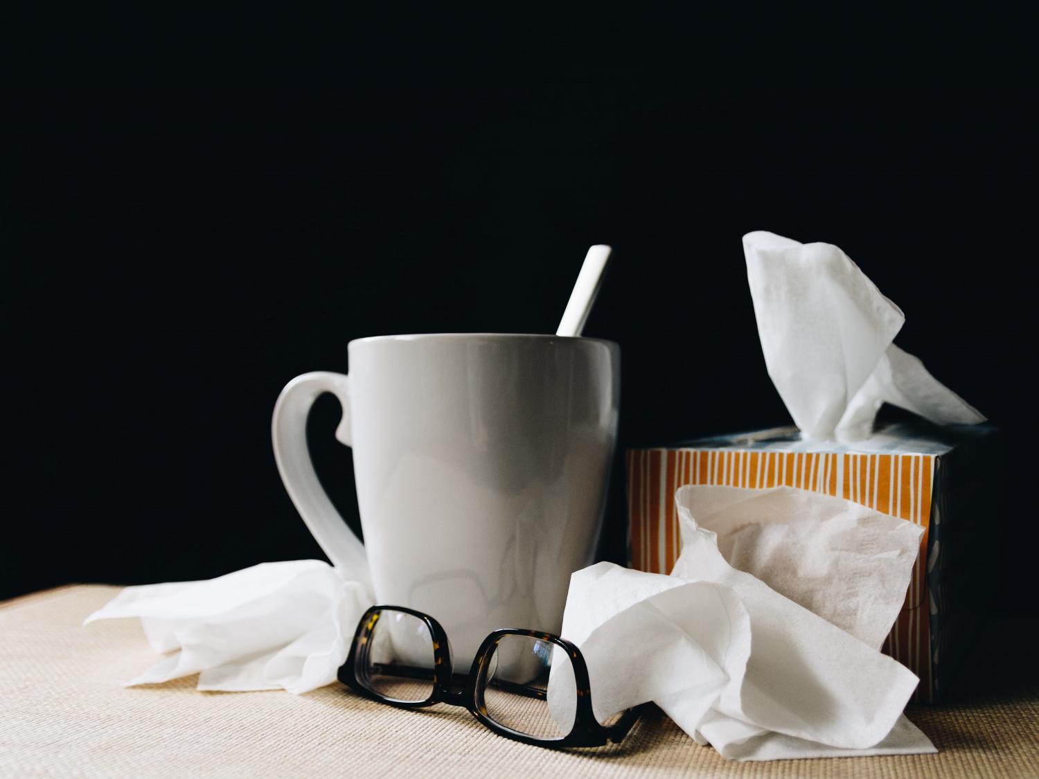 Tissues, tea, and other illness supplies arranged on a table