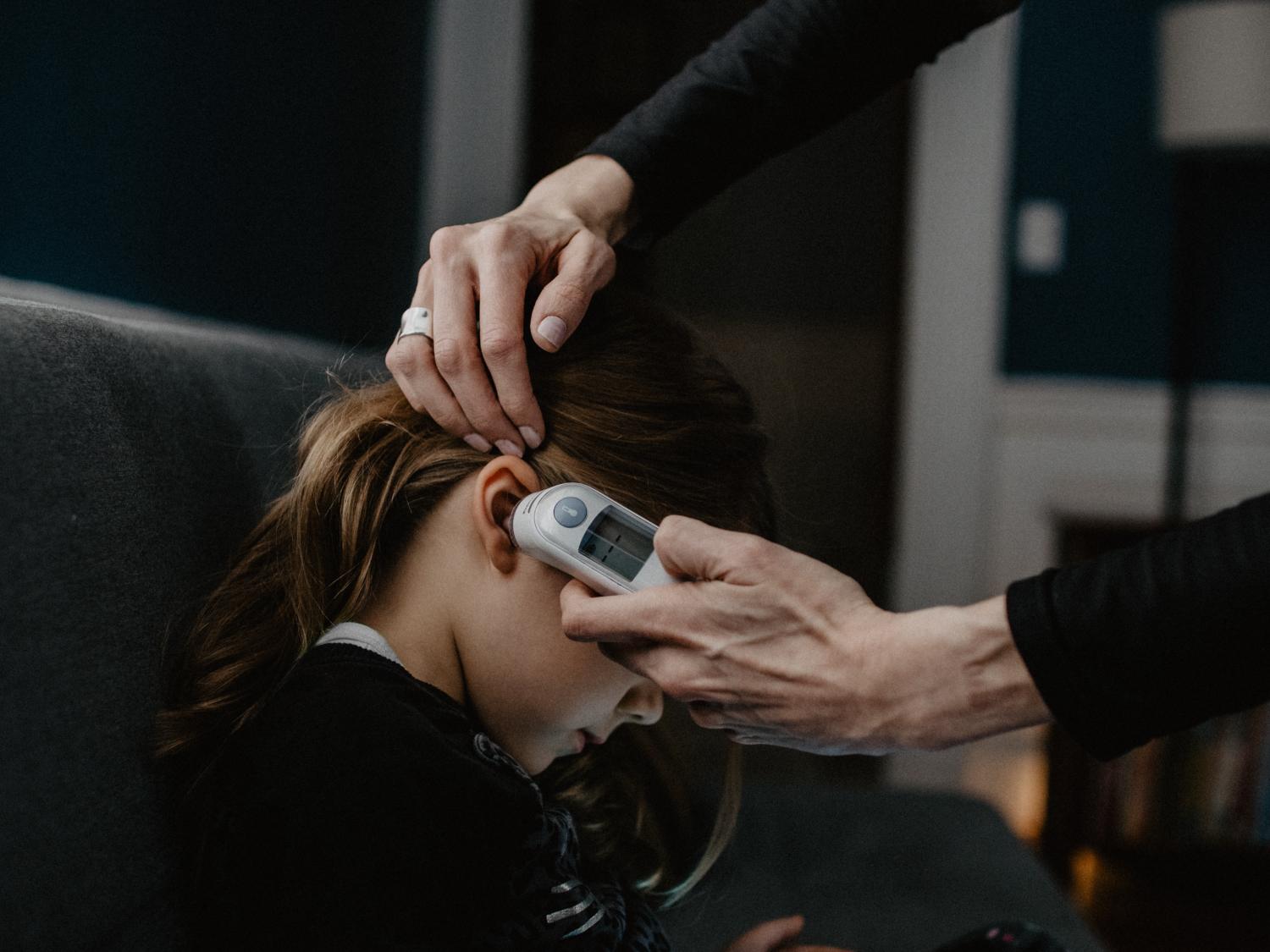 Child having temperature taken in ear.