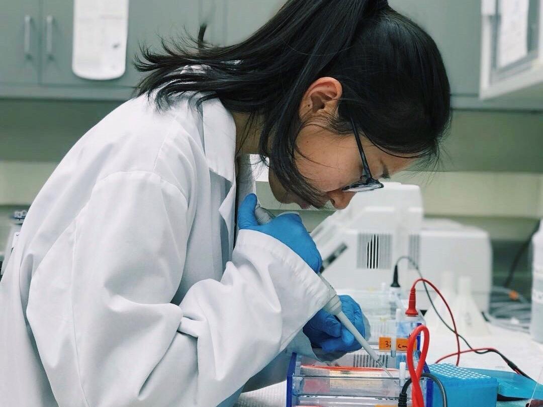 Asian woman looking through a microscope