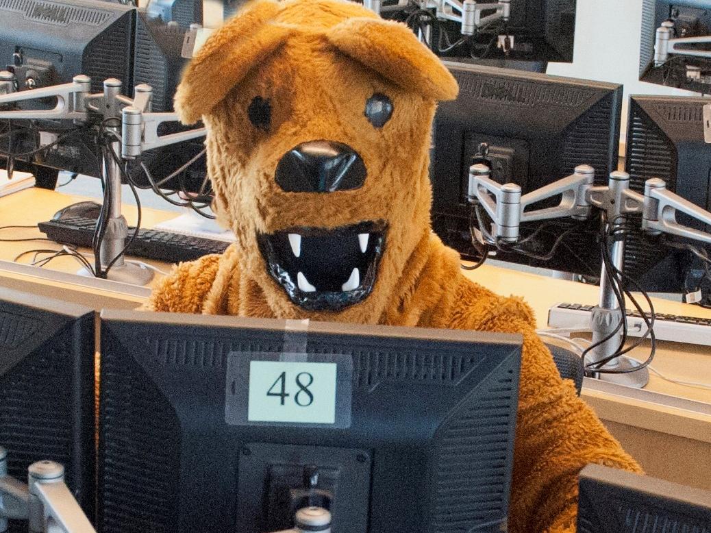 nittany lion mascot seated at computer in campus computer lab
