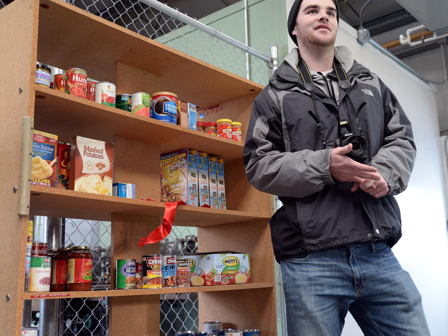 Student talks about Lion's Pantry effort in front of food shelf