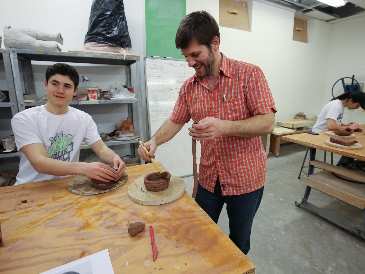 Students around a table making ceramic pots. 