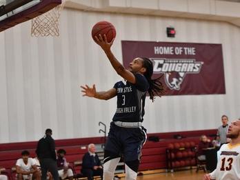men's basketball player jumping up to the basket to score