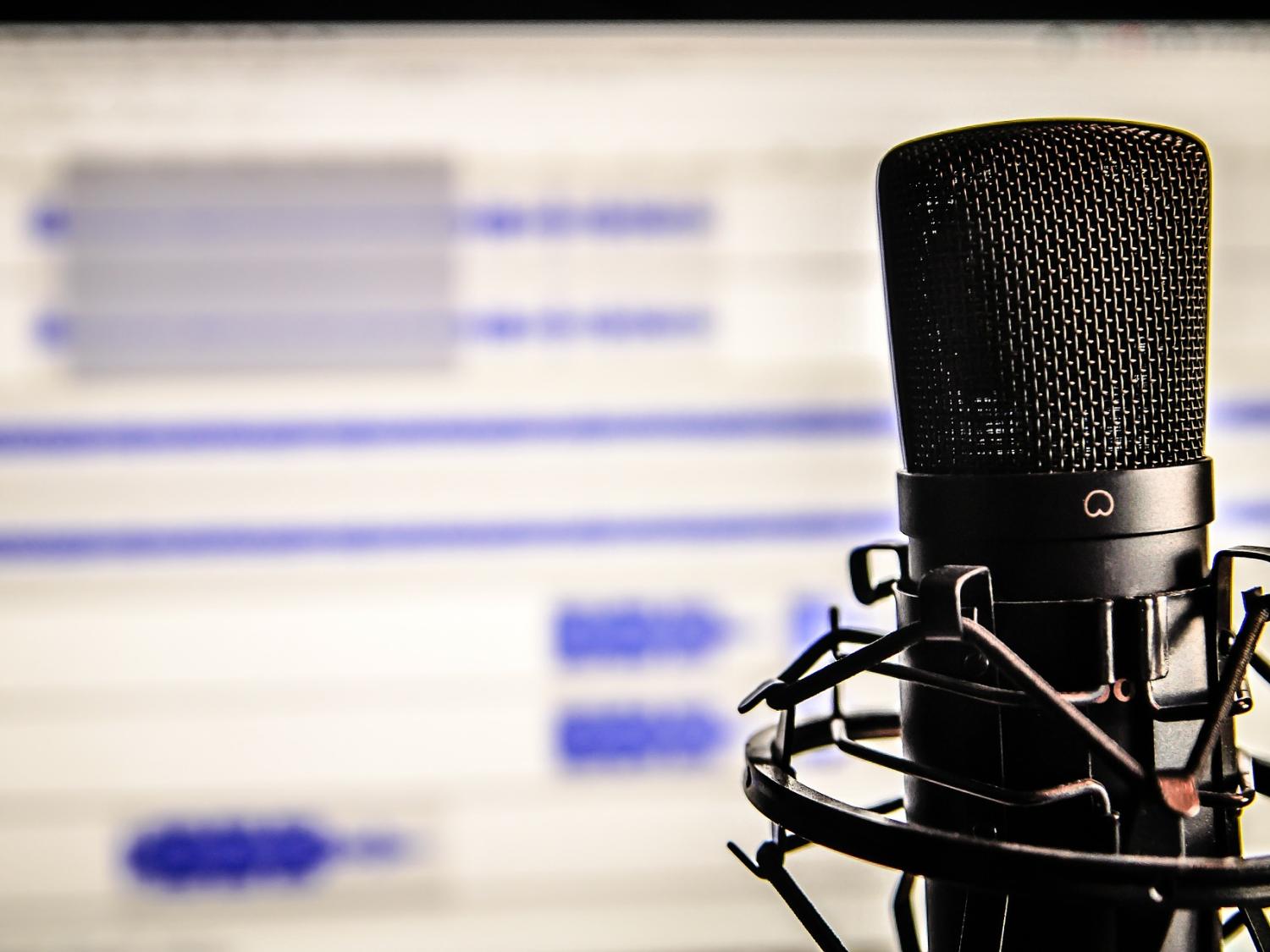 A microphone rests in front of a blurred, white computer screen