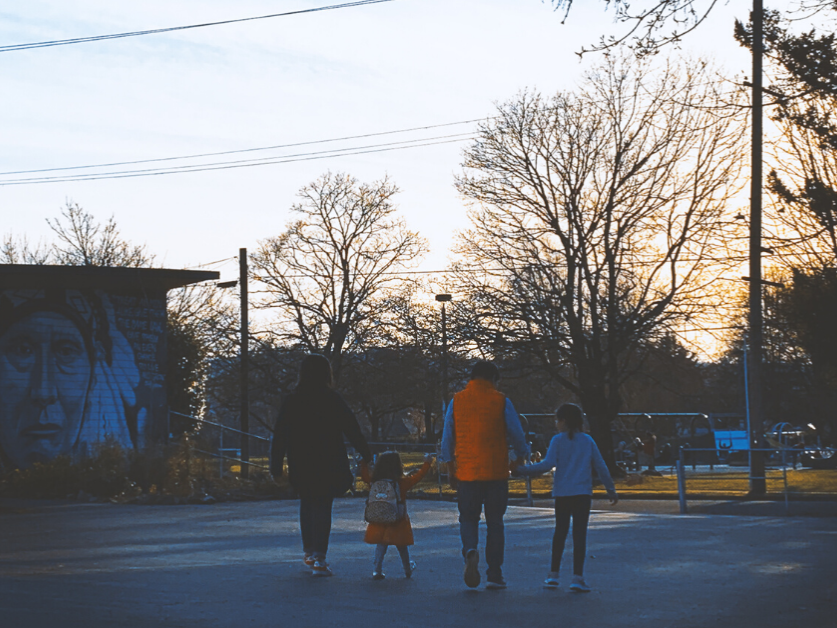 A family walks hand-in-hand down an empty street.