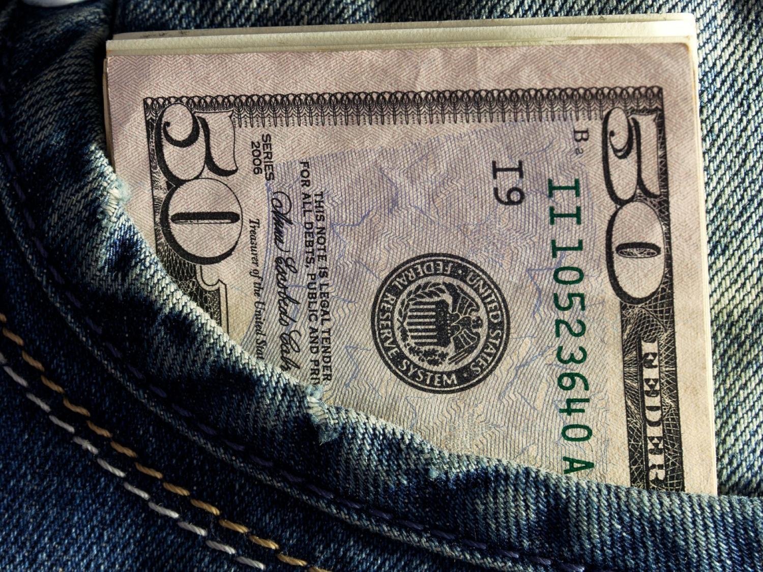 closeup image of folded 50 dollar bills in jeans pocket