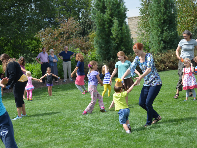 Children and their families spin in circles on the lawn of the Arboretum at Penn State.
