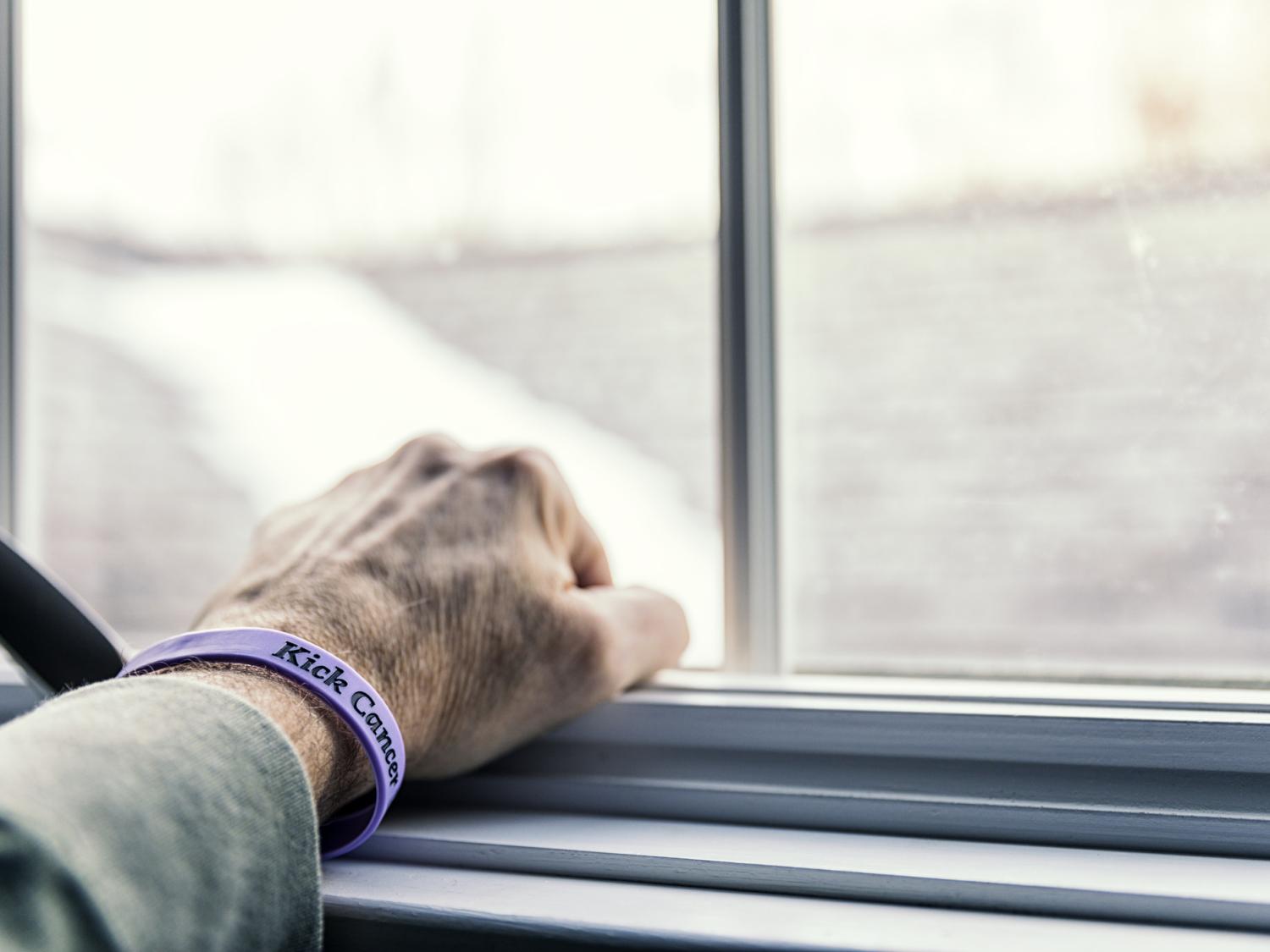 The hand of an elderly patient resting on a windowsill