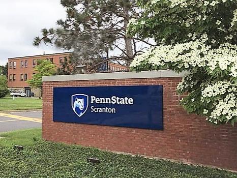 Front entrance to campus with brick wall and sign