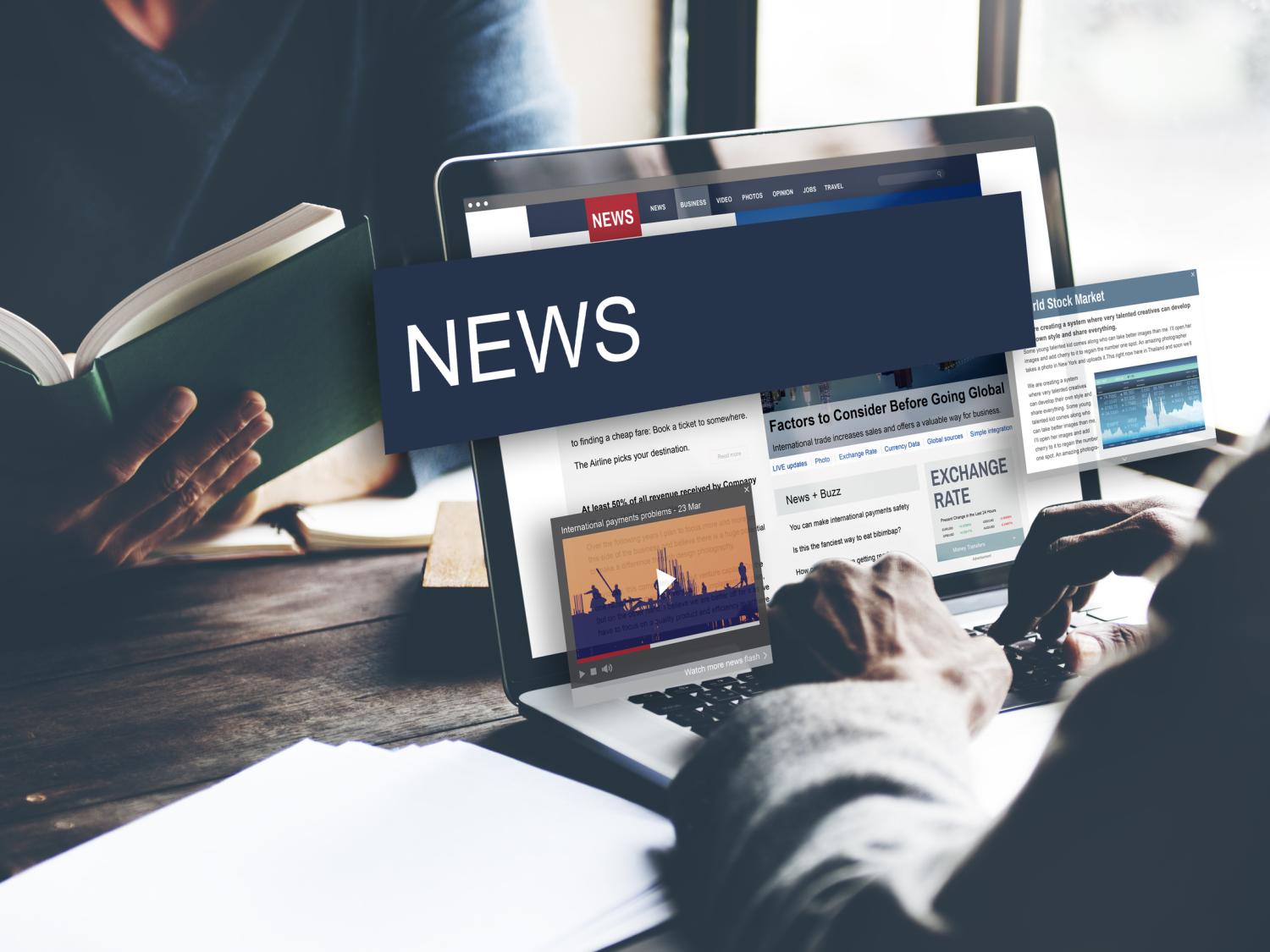 A man sits at a laptop reading the news