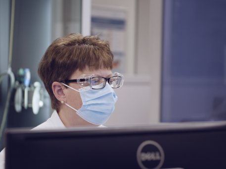 Woman in face mask reviewing work in lab