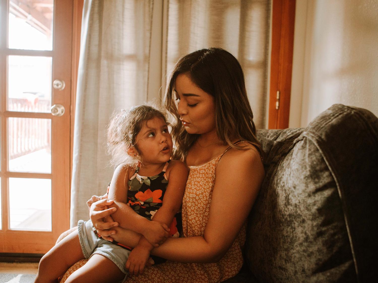 Woman holding young daughter on lap.