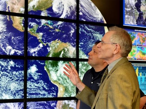 Meteorologists in front of digital map wall