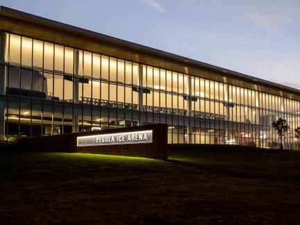 Pegula Ice Arena with lights on at dusk
