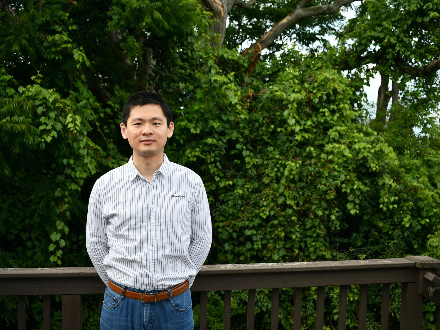  A professor stands in front of trees.