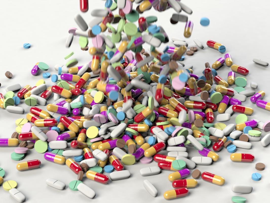 A few hundred pills of various types are dumped onto a plain space.