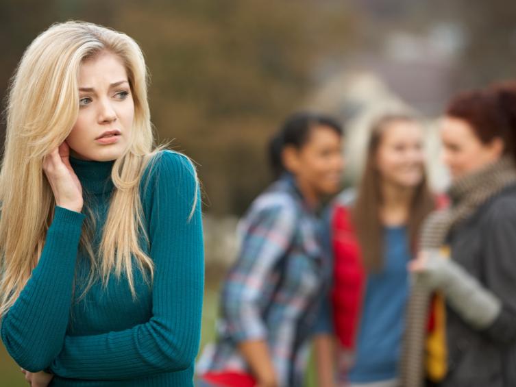 pretty blond girl with friends gossiping in background
