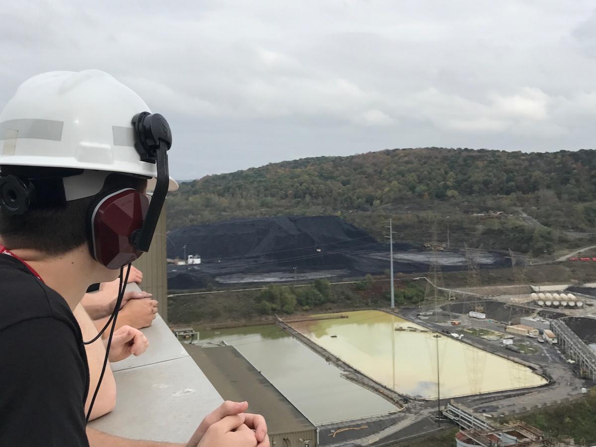 A student wearing a construction hat looks down from the 17th floor of a building.