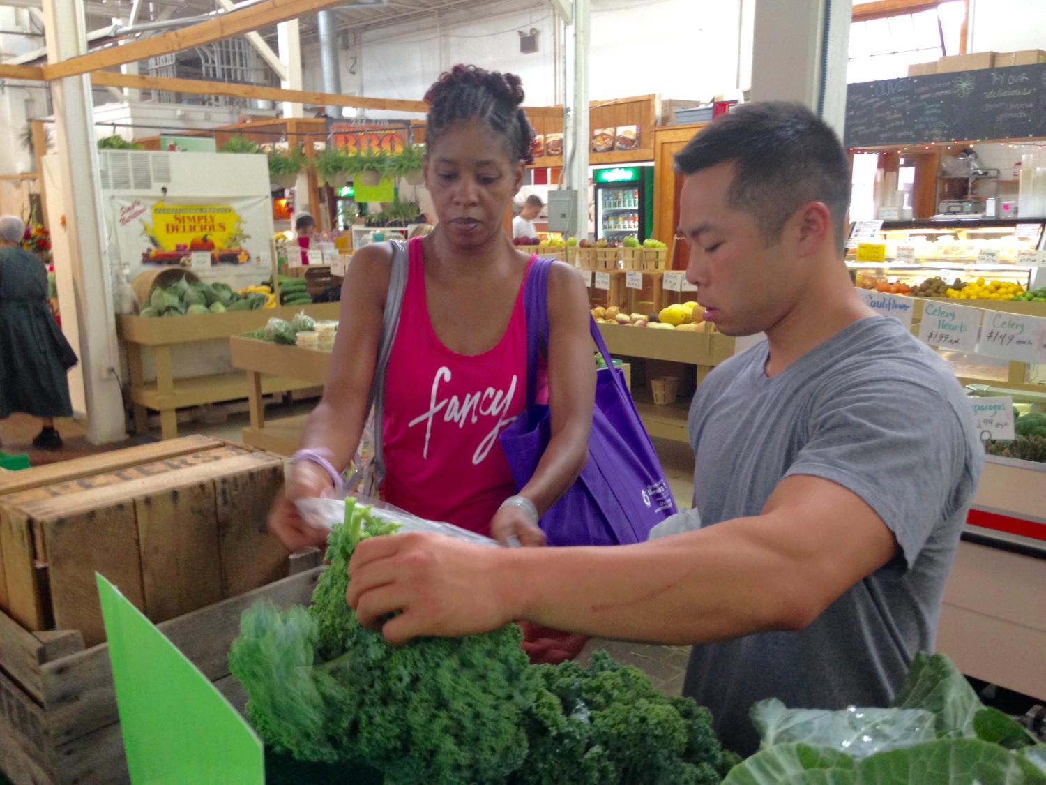 John Chan, a medical student who helped develop the Prevention Produce program, helps a participant choose vegetables.