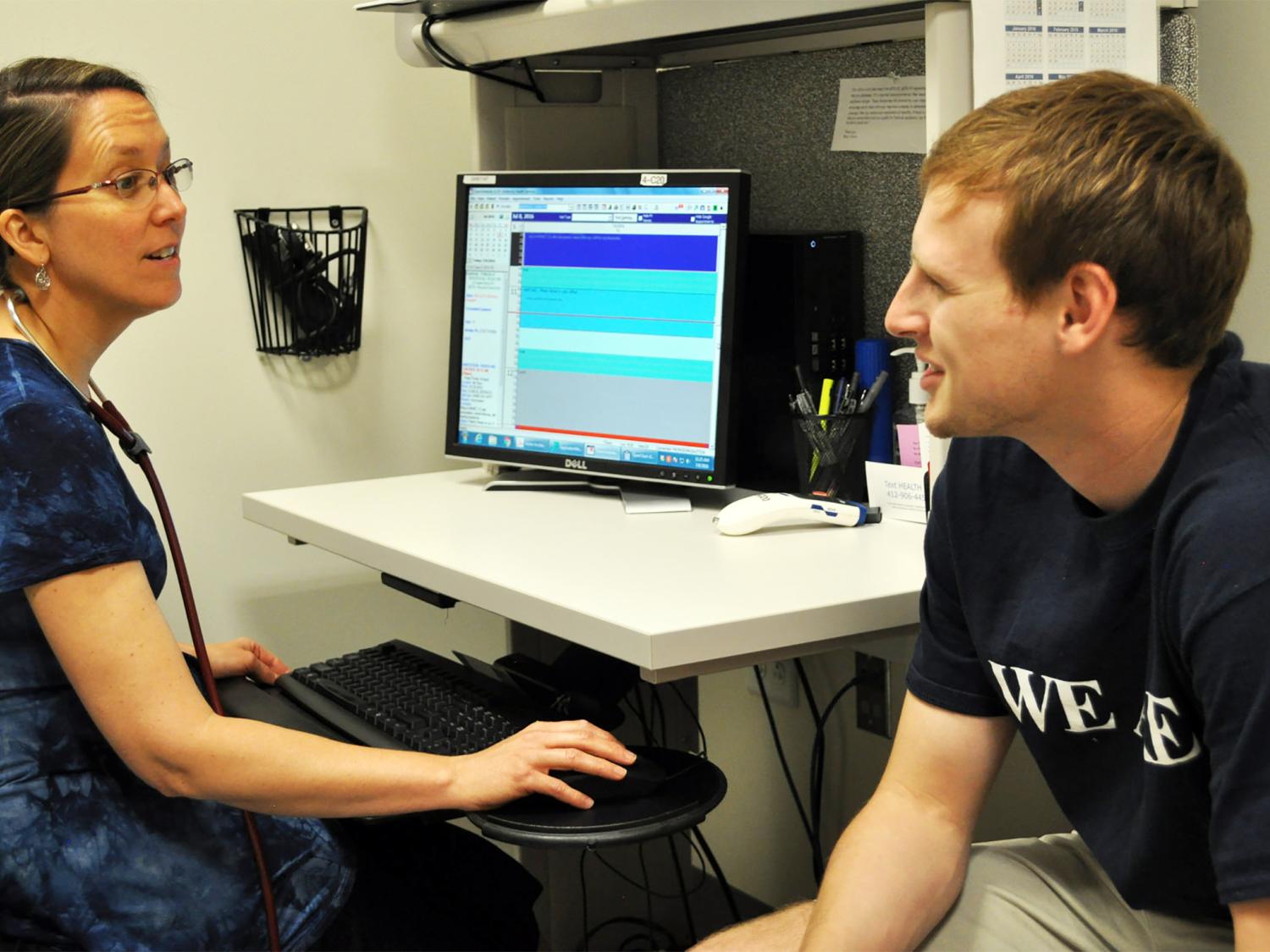 Male student conversing with female health care provider during office visit