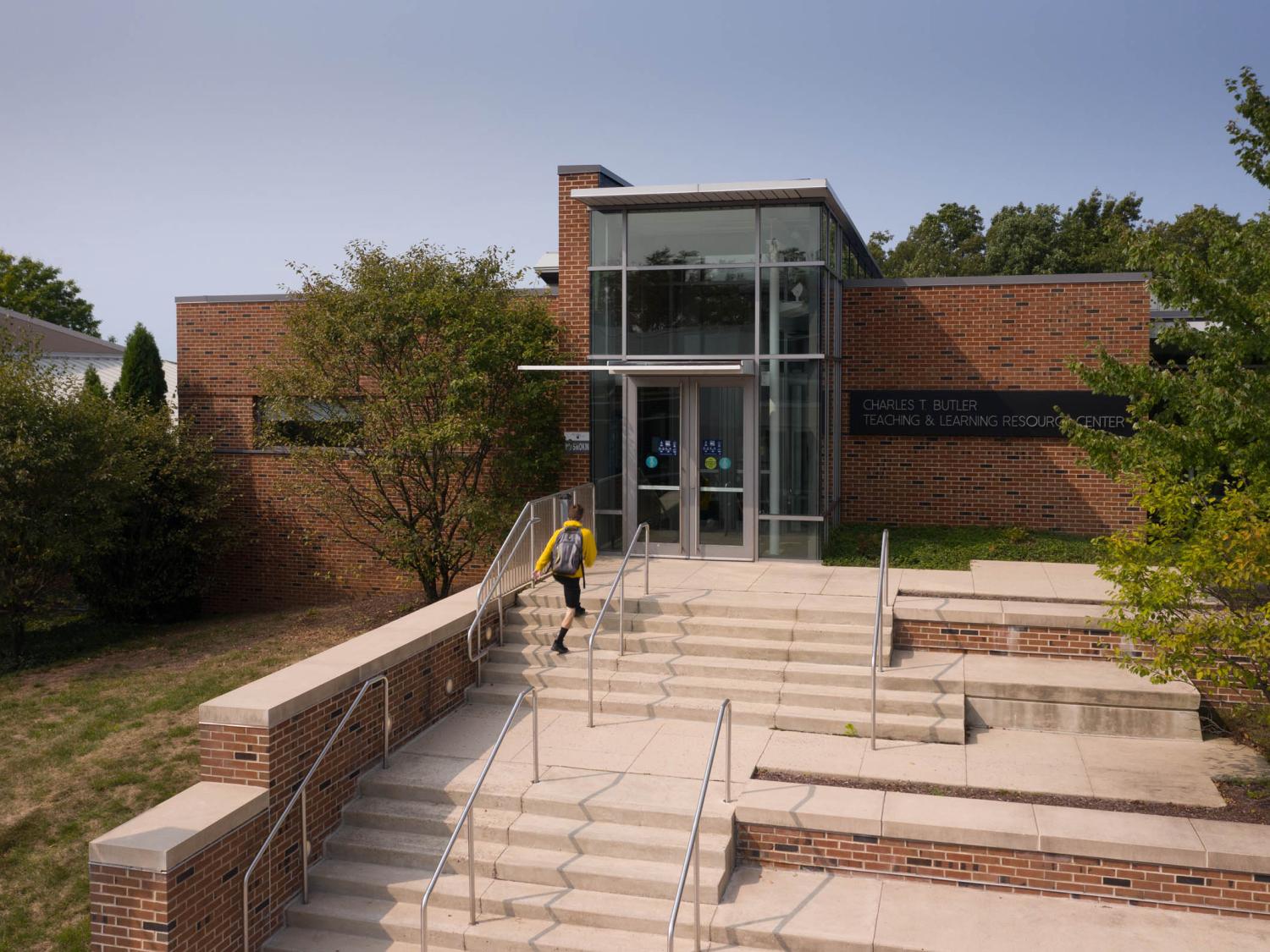 Student walking up stairs to brick building entrance at Penn State Hazleton.