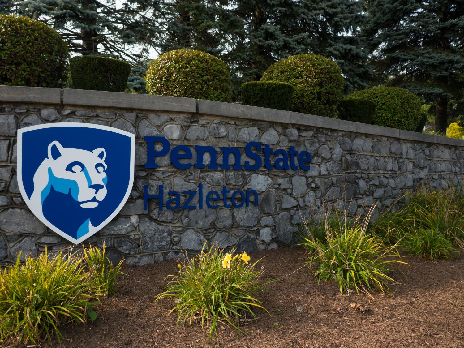 Entrance to Penn State Hazleton with stone wall featuring campus logo