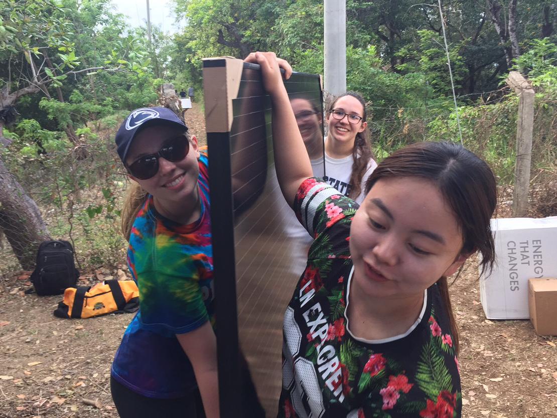 students carrying solar panel
