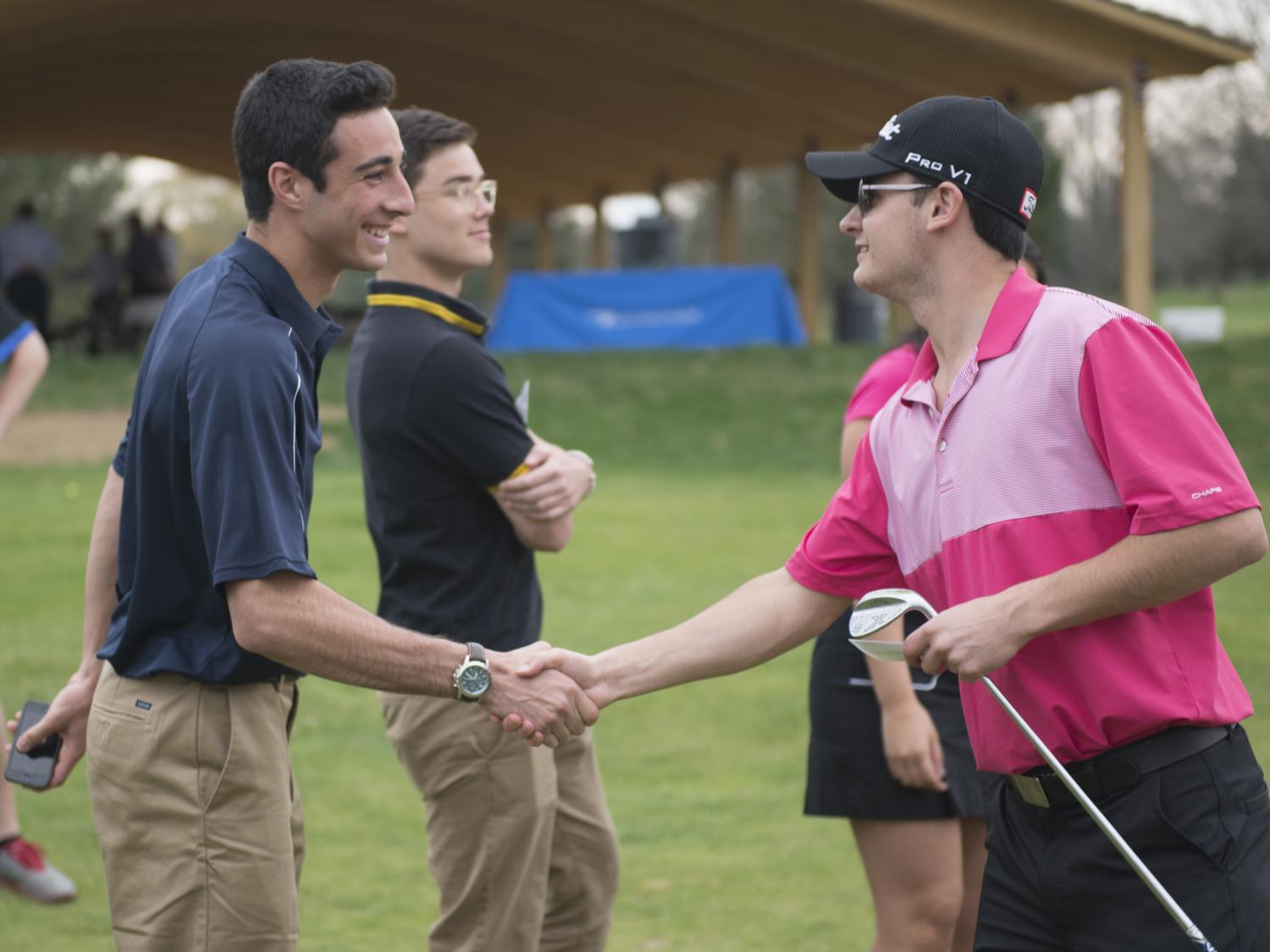 Students shake hands on the golf course