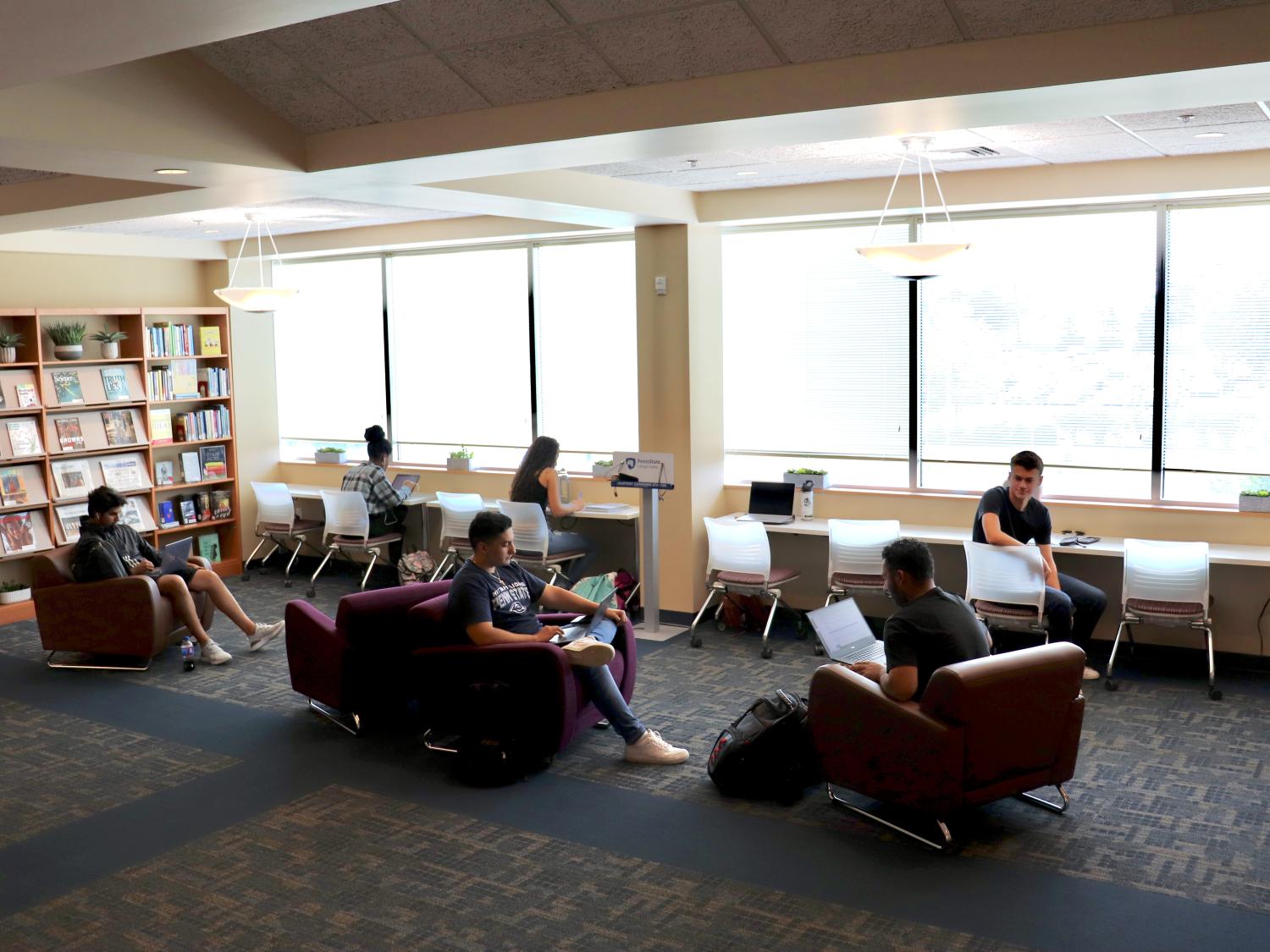students studying in lounge chairs and desk chairs in library